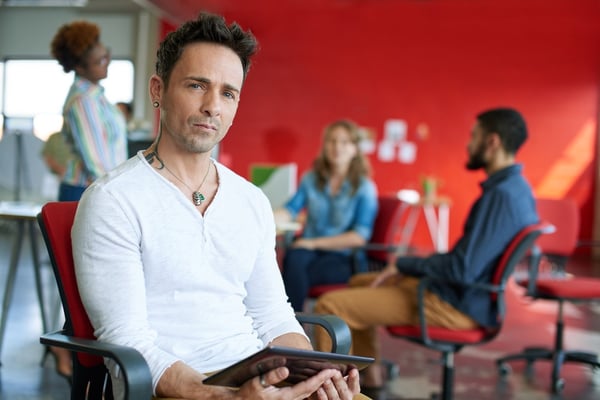 Confident male designer working on a digital tablet in network meeting