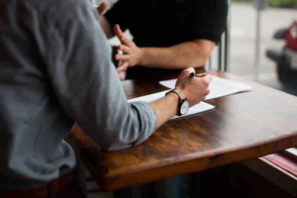 Two people talking and making notes